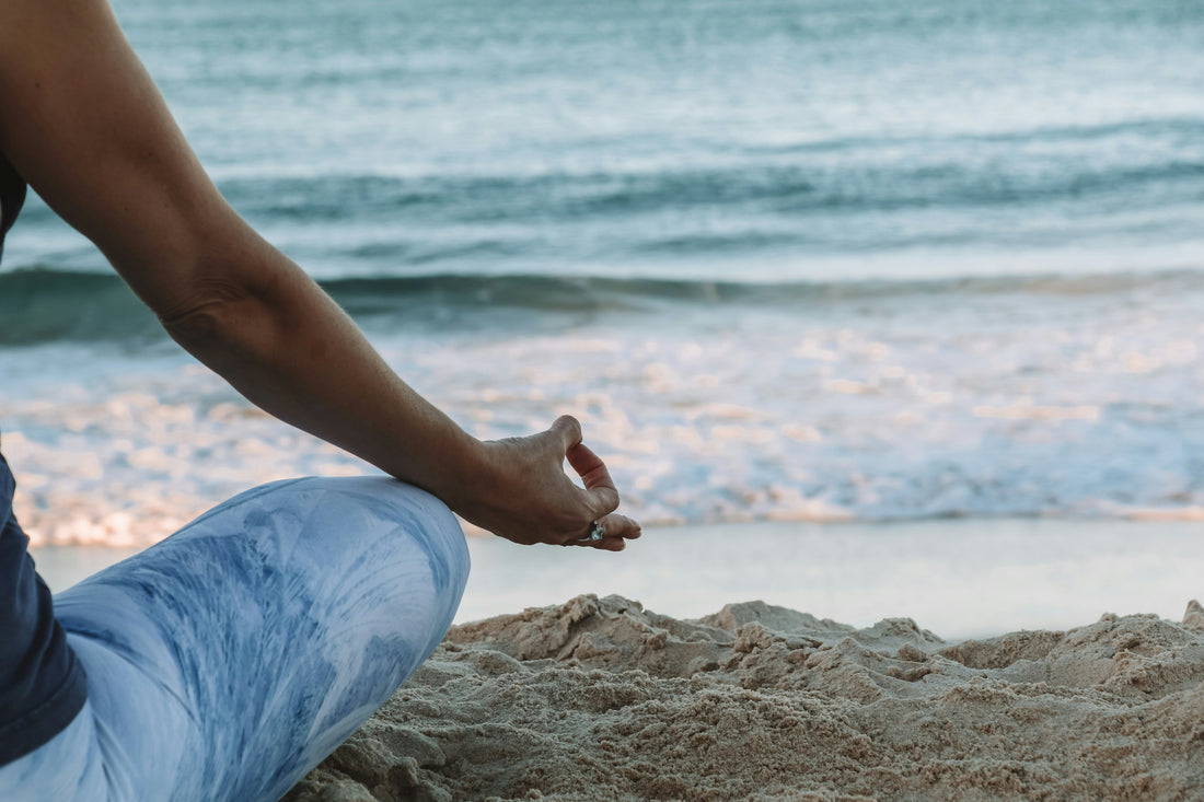 Femme en position de yoga devant une plage 